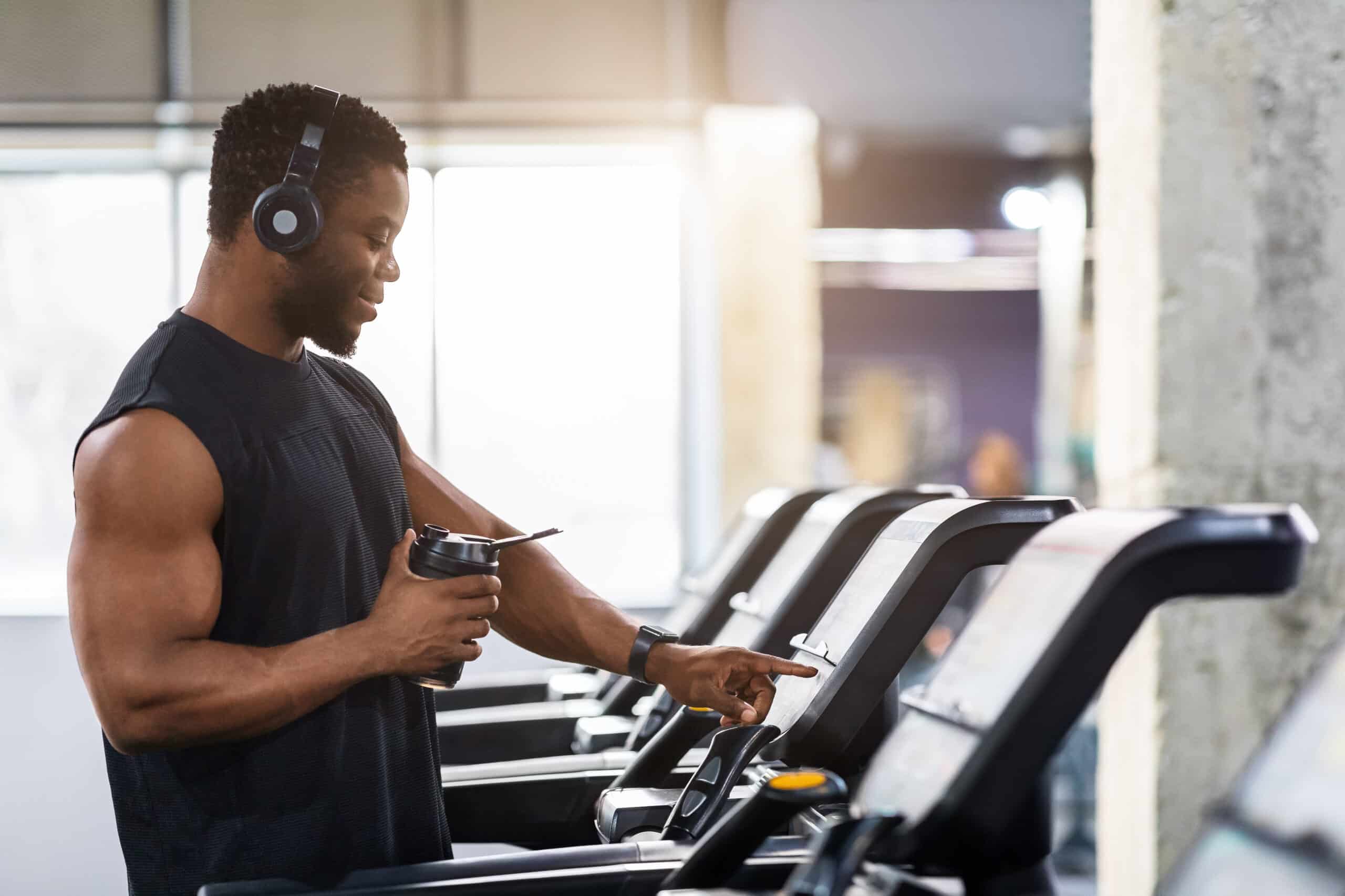 Muscular African American Man With Protein Drink Standing On Treadmill